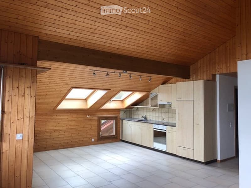 Bright, wooden-paneled kitchen with white tiled floor, built-in cabinets, sink, and oven. Features skylights and a window for natural light.