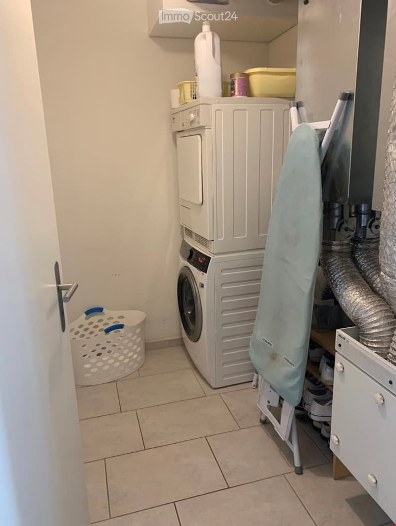 Laundry area with a washing machine, dryer, ironing board, and storage shelves.