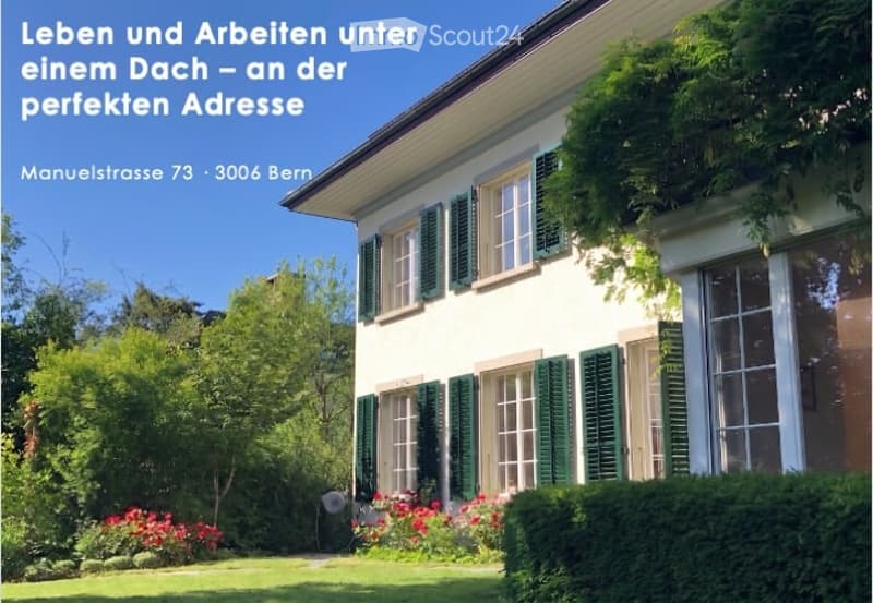 A two-story house with white walls, green shutters, and a well-maintained garden with red flowers and green shrubs.