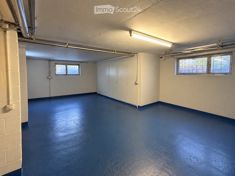 Empty room with white brick walls, blue painted floor, white cabinet, and windows with metal bars.
