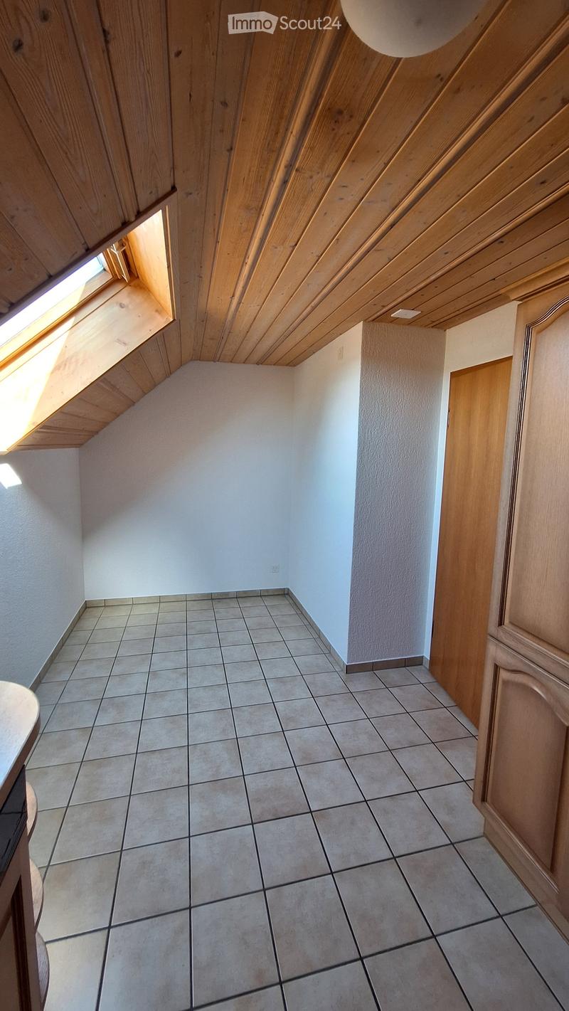 Empty hallway with tiled floor, light-colored walls, wooden ceiling, and a small window letting in natural light.