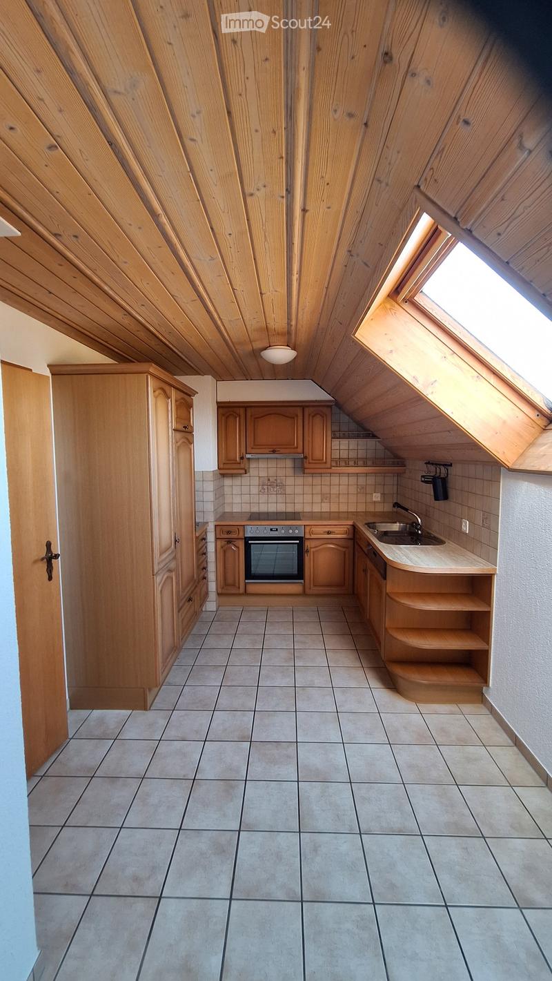 Bright kitchen with wooden cabinets, tiled floor, and a skylight window. Features an oven, sink, and built-in shelves.
