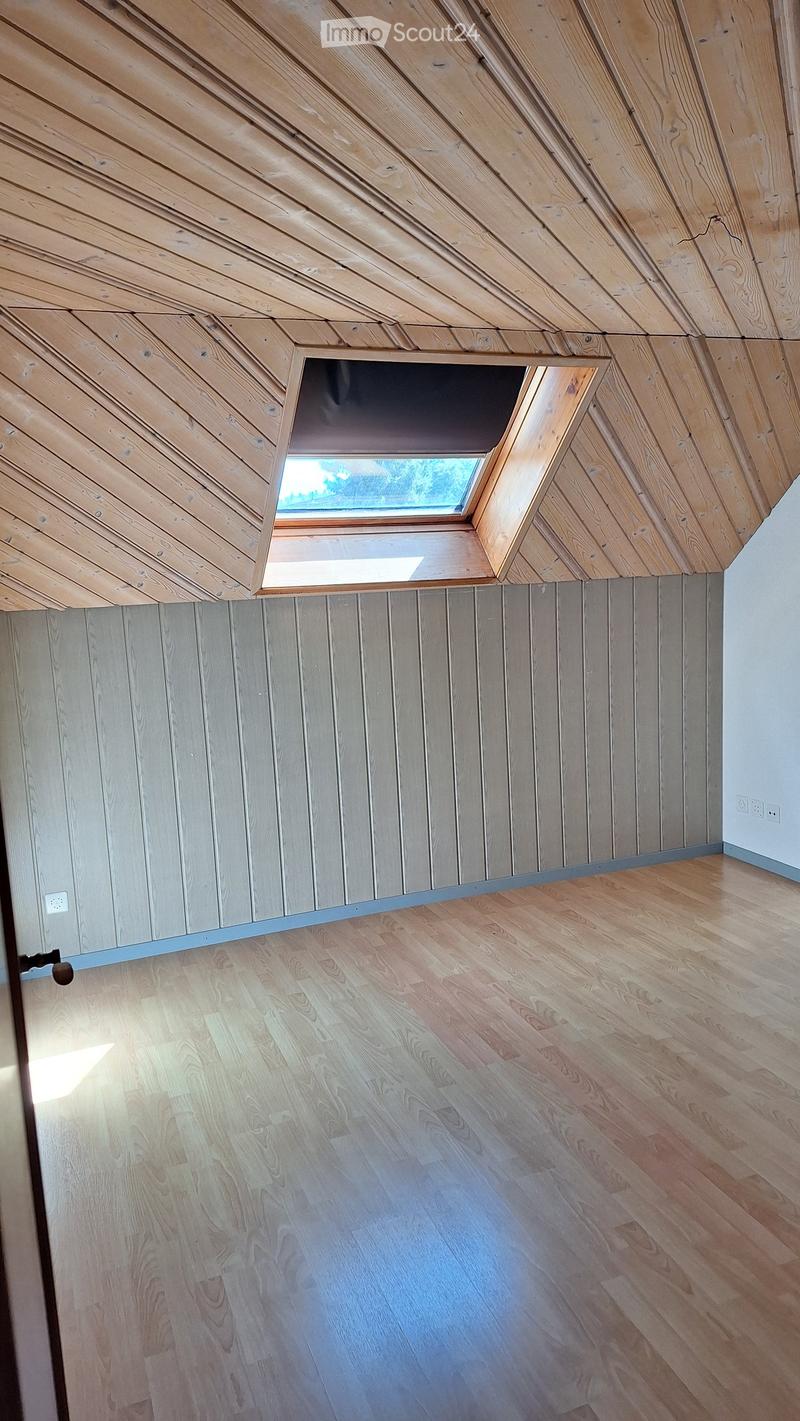 Empty room with wooden walls, wooden ceiling, and wooden floor. A skylight window is present in the ceiling.