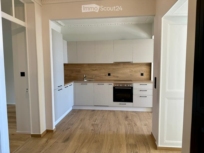 Modern kitchen with white cabinets, wooden countertop, and integrated appliances including a sink and oven.