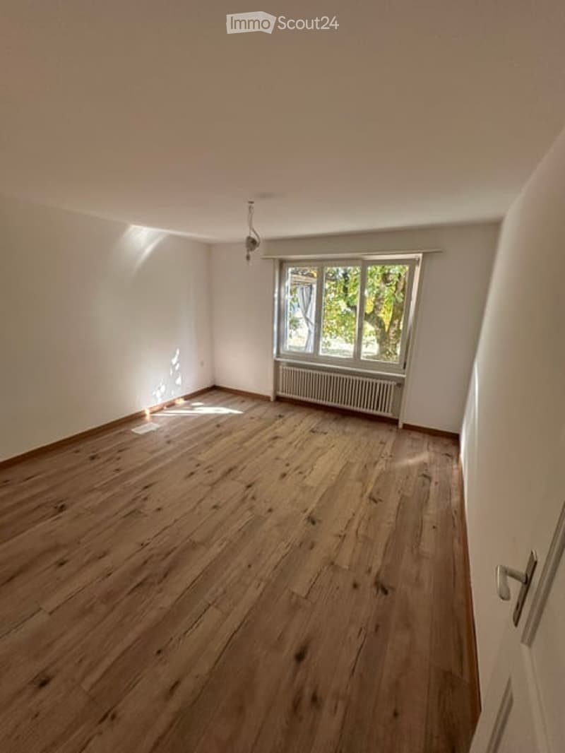 Empty room with wooden flooring, white walls, and a window with a radiator below it. No furniture or equipment is present.
