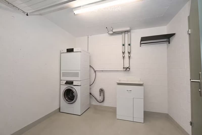 Clean, modern bathroom with a stacked washer/dryer unit, a small sink with cabinet, and white tiled walls.