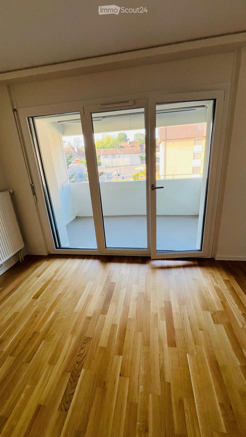 Empty room with wooden flooring and large sliding glass doors leading to a balcony.