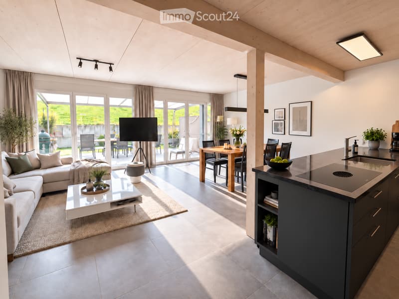 Open-plan living and dining area with a modern sofa, coffee table, dining table, and kitchen island. Large windows and sliding doors lead to an outdoor patio.