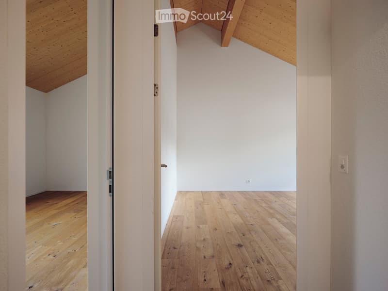 Unfurnished Room. Empty room with wooden flooring and white walls, featuring a wooden ceiling and a partially open door leading to another room.