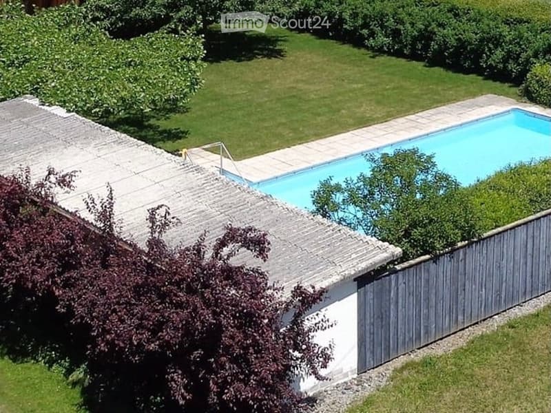 Aerial view of a private garden with a swimming pool, surrounded by a wooden fence and lush greenery.