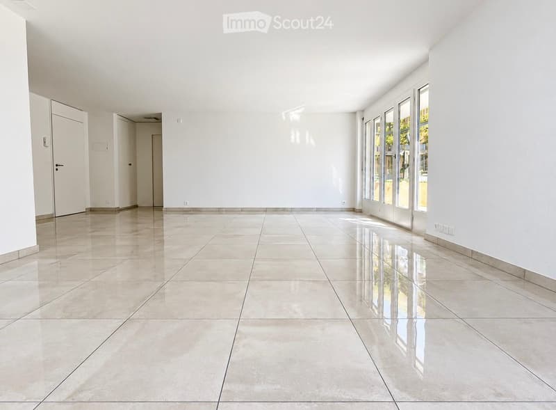 Empty room with white walls, polished tile floor, and large glass doors leading to an outdoor area.