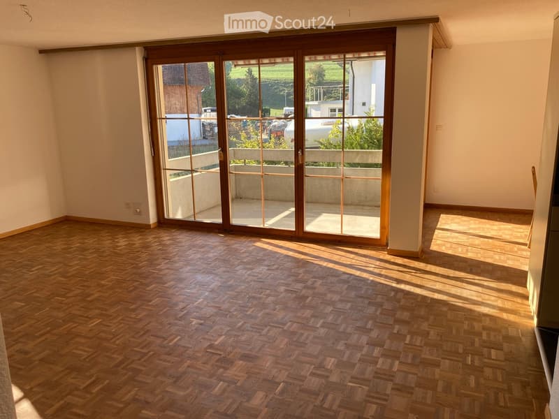 Empty room with wooden herringbone flooring and large sliding glass doors leading to a balcony or outdoor area.