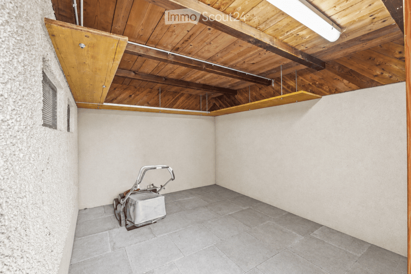 Empty room with a wooden ceiling, tiled floor, and a small window on one wall. A vacuum cleaner is placed in the corner.