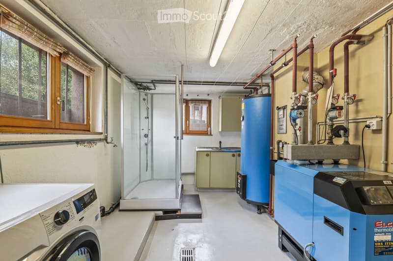 Utility bathroom with a washing machine, shower stall, cabinets, and water heater.
