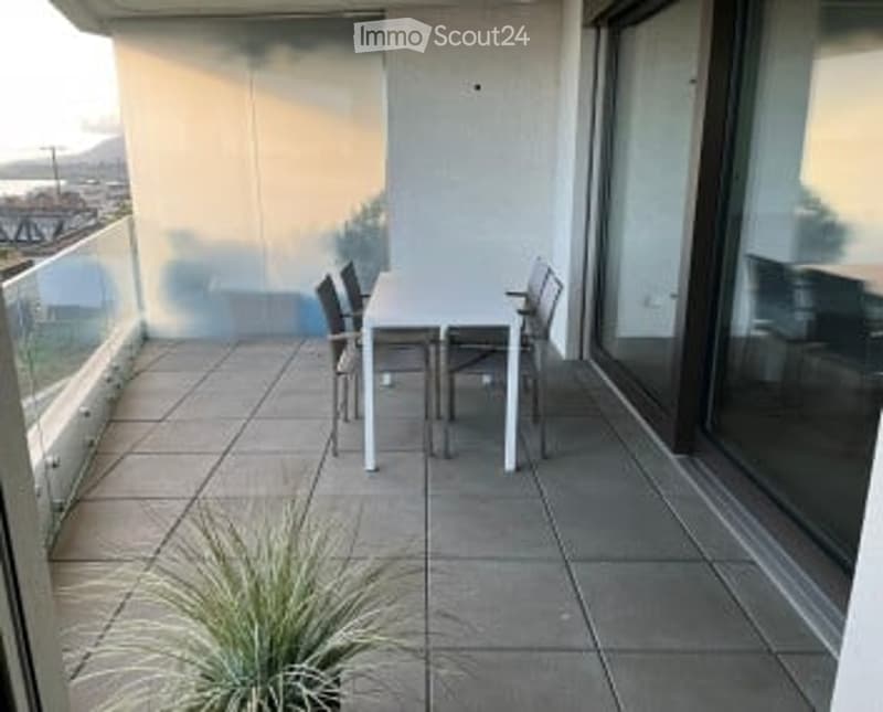 Balcony with tiled floor, white table, four chairs, and a small plant in the corner.