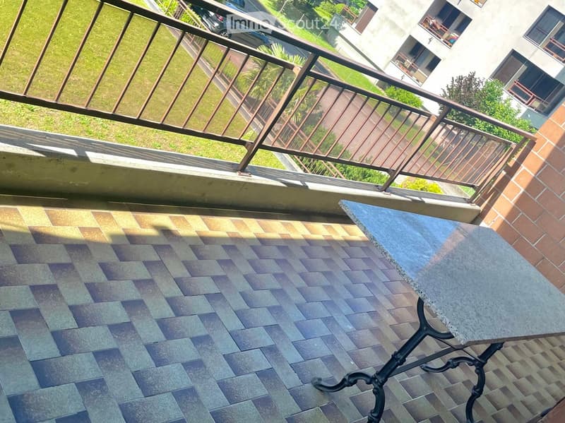 Balcony with tiled floor, metal railing, and a small table.