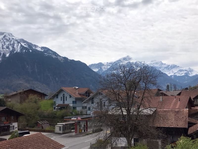A picturesque village scene with traditional houses and snow-capped mountains in the background.