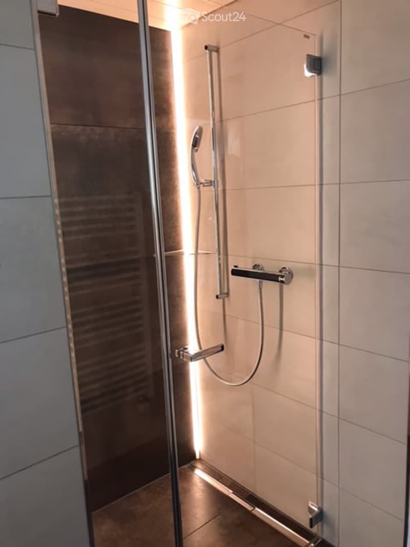 Modern shower area with glass enclosure, multiple shower handles, and sleek design.