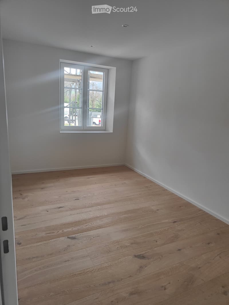 Empty room, hardwood floors, white walls, large window, hallway