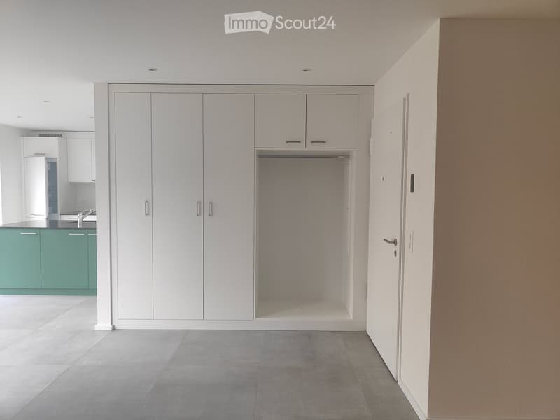 Empty room with white wardrobe, green kitchen cupboards, grey tiled floor, sink with faucet