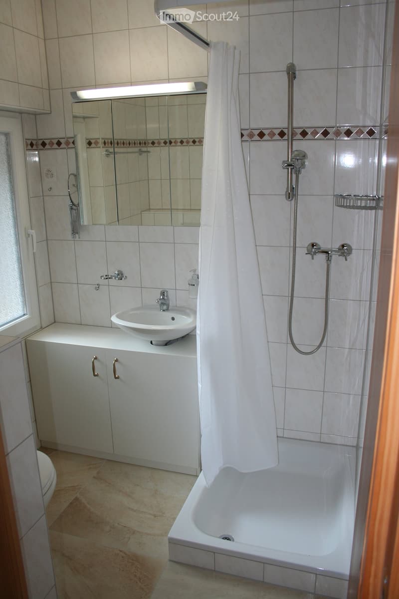 Modern bathroom with a bathtub, shower area, sink, mirror, and white cabinets.