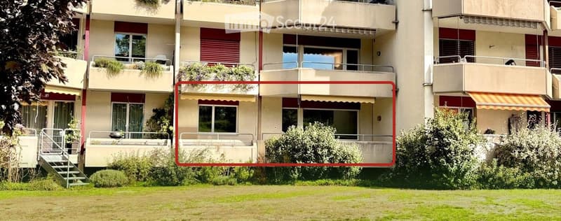 Multi-story residential building with balconies, windows, and greenery.