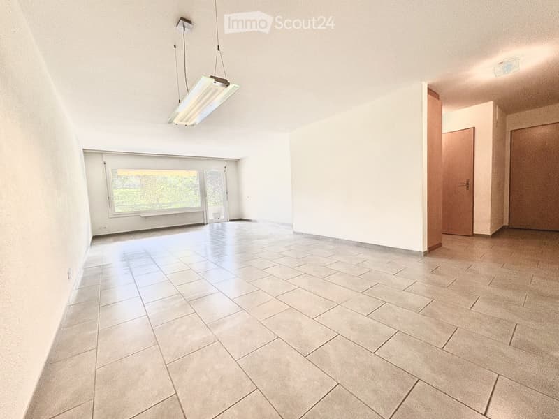 Empty room with tiled floor, white walls, large window, and pendant light fixture.