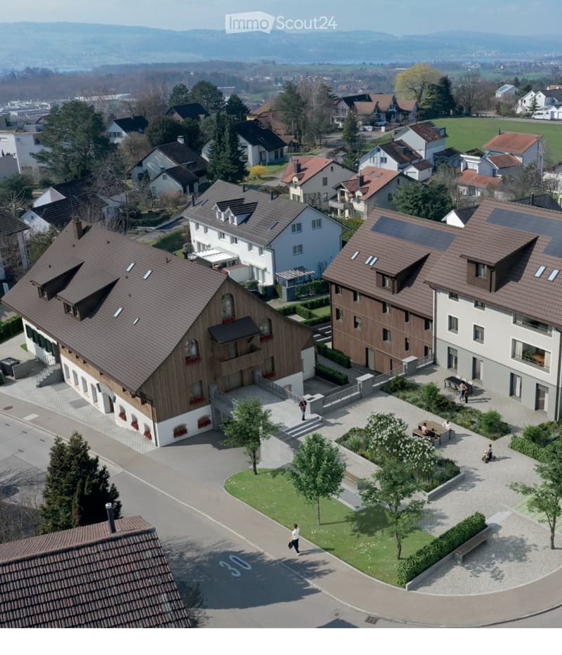 Aerial view of a residential area with multiple houses, gardens, and a central courtyard with seating and greenery.
