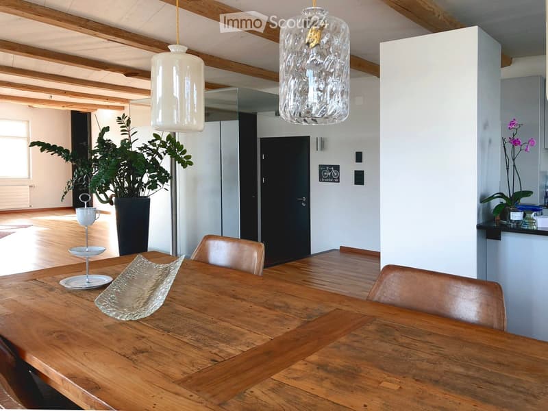 Dining area with wooden table, chairs, pendant lights, and decorative items.