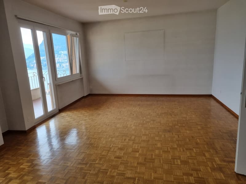 Empty room with wooden flooring, large windows offering a scenic view, and white walls.