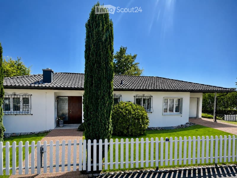 Two-story house with white exterior, dark roof, and a well-maintained garden with a white picket fence.