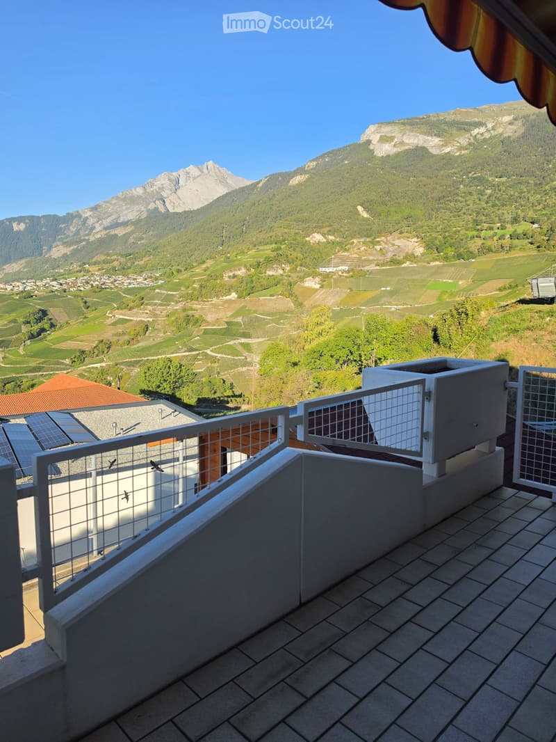 Balcony with tiled floor, metal railing, and a scenic mountain view in the background.