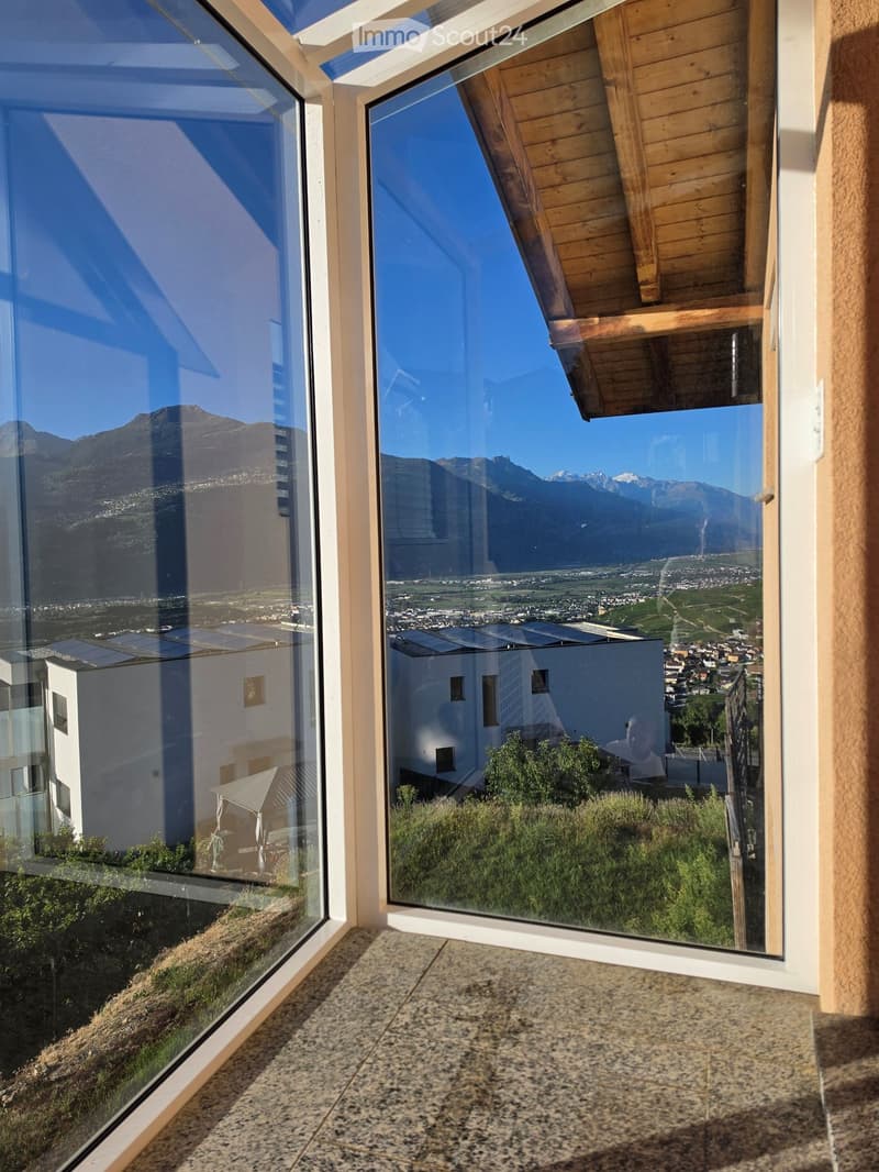 Balcony with large glass windows offering panoramic mountain and city views, wooden slatted roof, granite tiled floor.