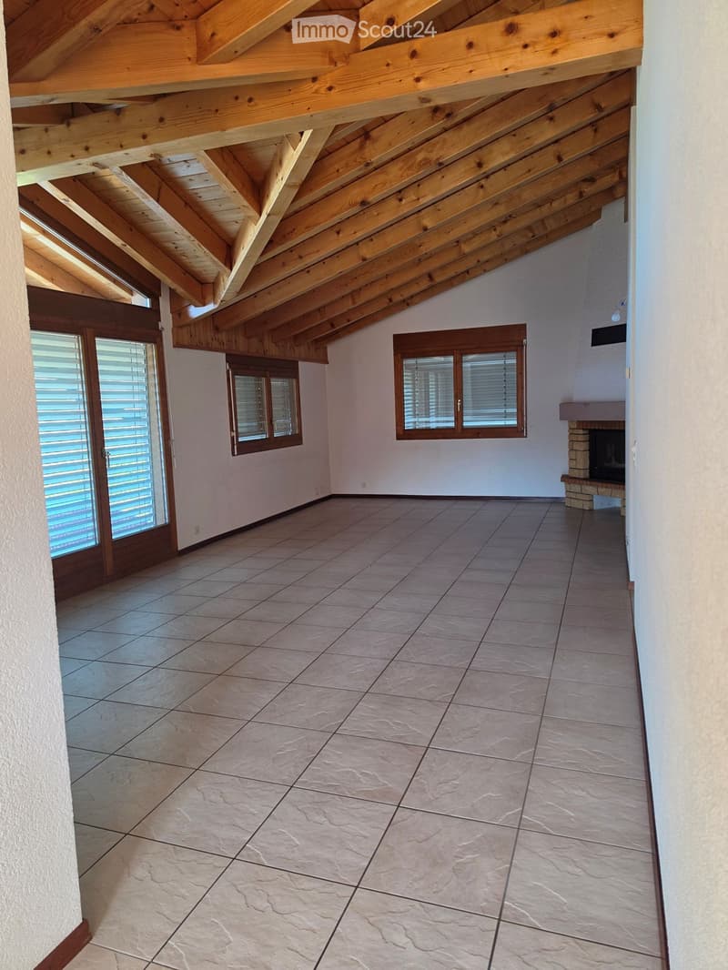 Empty room with exposed wooden beams on the ceiling, tiled floor, and a fireplace on the right side.