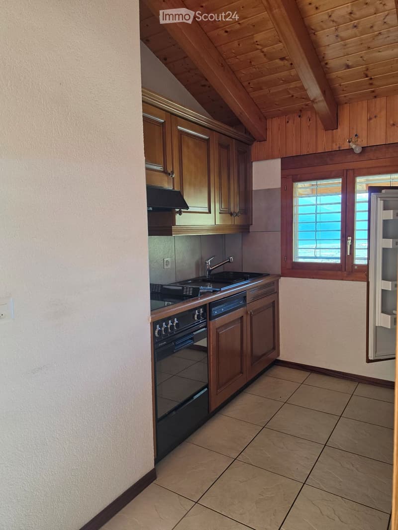 Modern kitchen with wooden cabinets, stainless steel appliances, and a tiled floor. Features an oven, dishwasher, sink, and refrigerator.