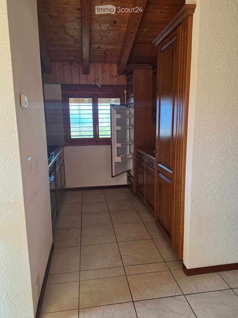 Narrow hallway with wooden ceiling, tiled floor, and built-in cabinets. A small window with blinds offers a view of the outdoors.
