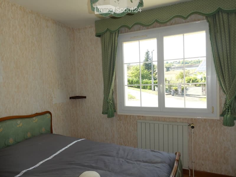 Bedroom with a single bed, green curtains, radiator, and a window overlooking a garden.