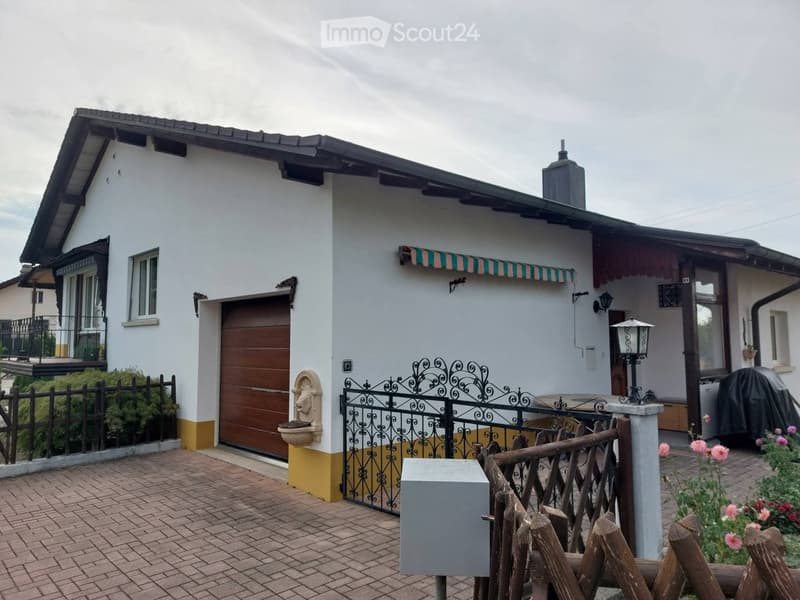 Two-story house with white exterior, garage, decorative fence, and outdoor seating area.
