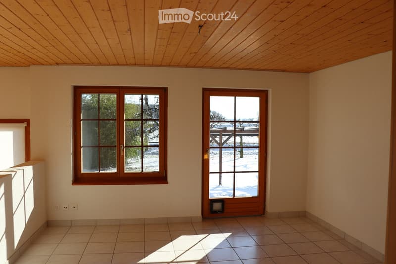Empty room with tiled floor, light-colored walls, and large windows and doors leading to an outdoor area with snow-covered ground.