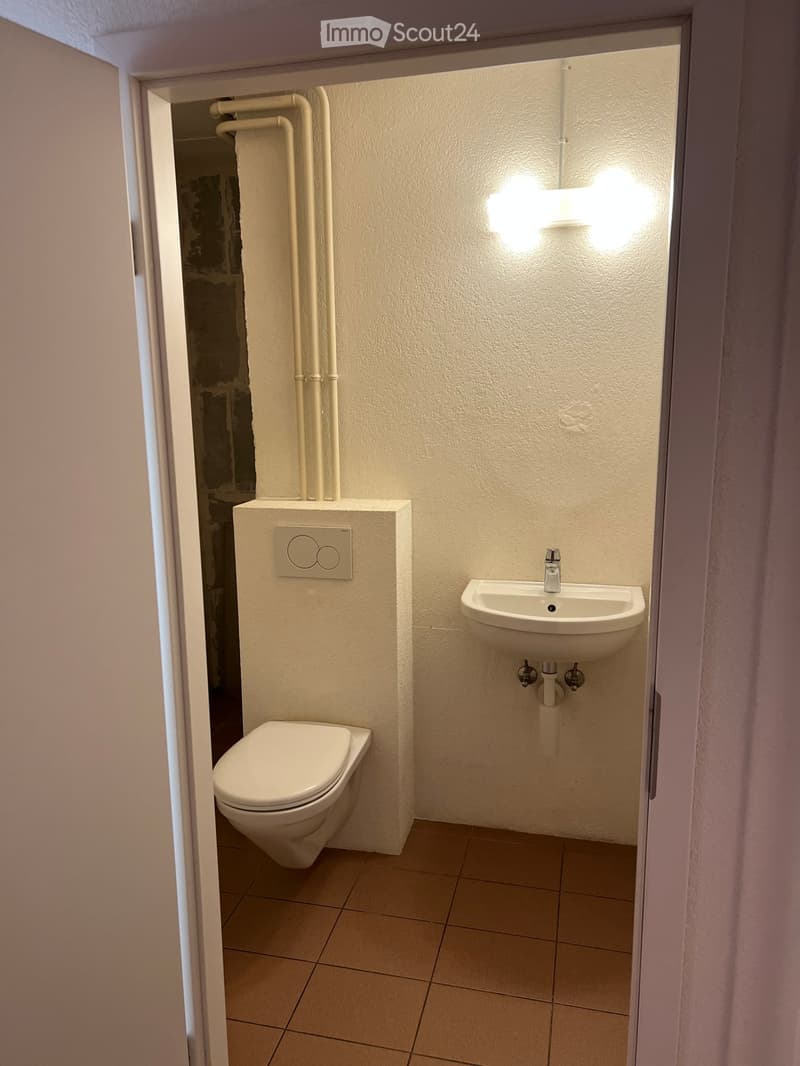Small bathroom with a toilet, sink, and faucet, featuring tiled flooring and white walls.