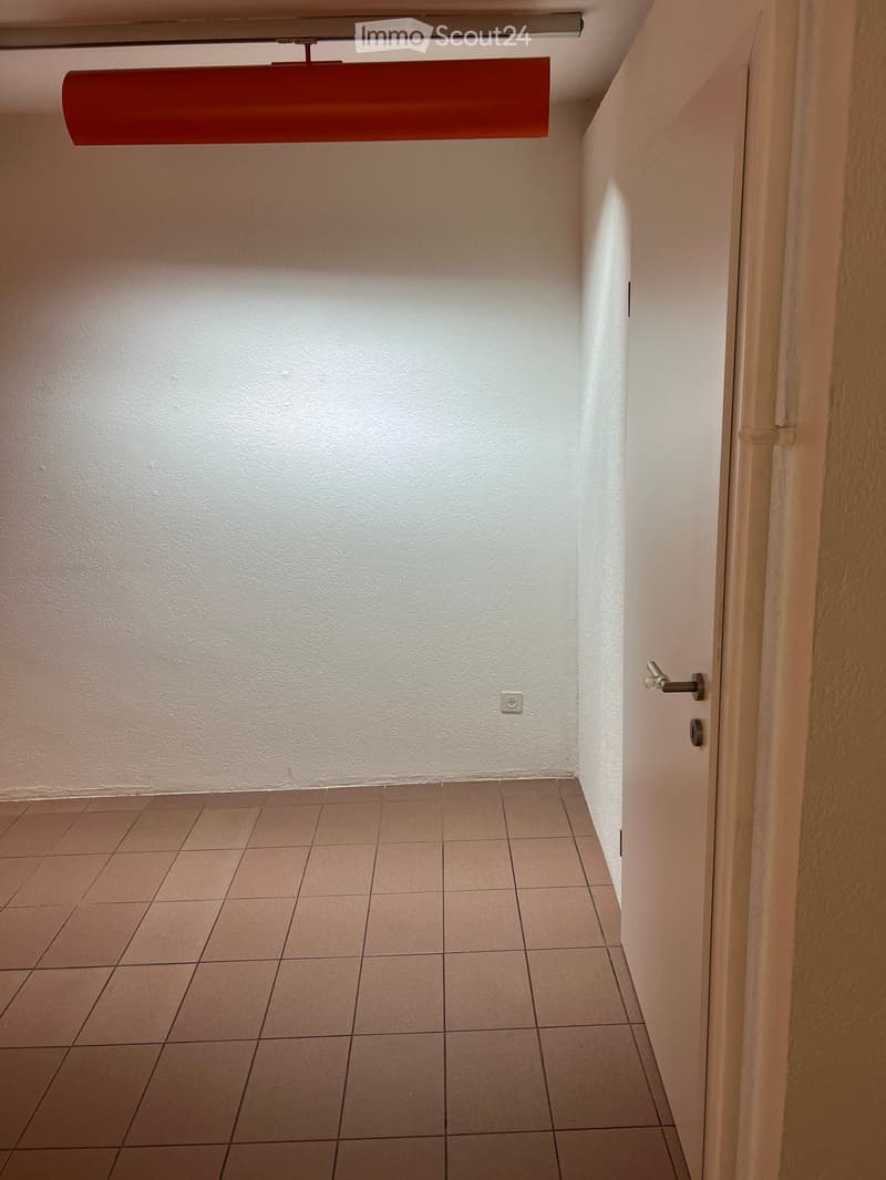 Empty hallway with tiled floor, white walls, and a closed door on the right side.