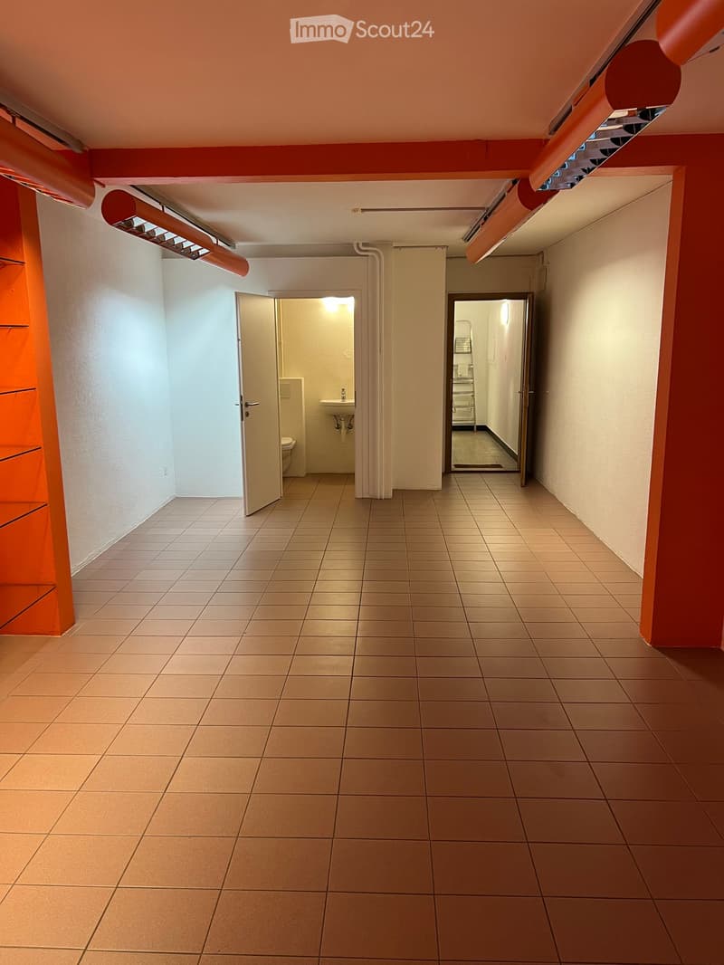Empty hallway with tiled floor, white walls, and two open doors leading to bathrooms.