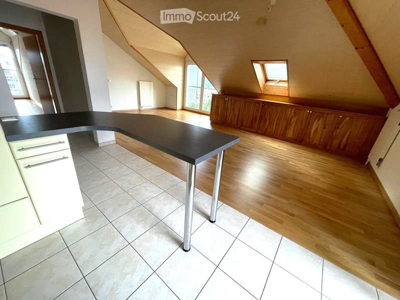 Modern kitchen with wooden cabinets, a black countertop, and a mix of tiled and wooden flooring.