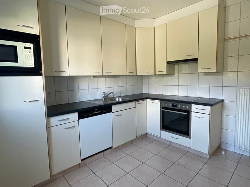 Modern kitchen with white cabinets, black countertops, and stainless steel appliances including a refrigerator, microwave, dishwasher, and oven. Features a sink with a faucet and tiled walls.