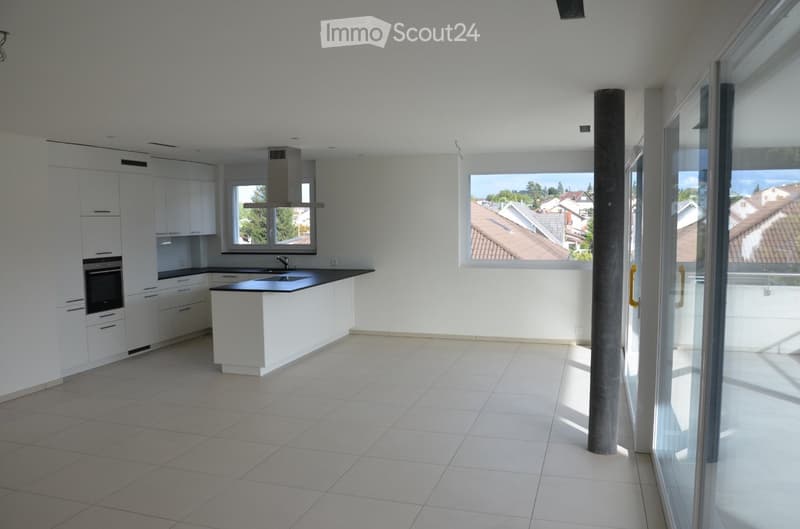 Modern kitchen with white cabinets, a central island, and large windows offering a view of the neighborhood.