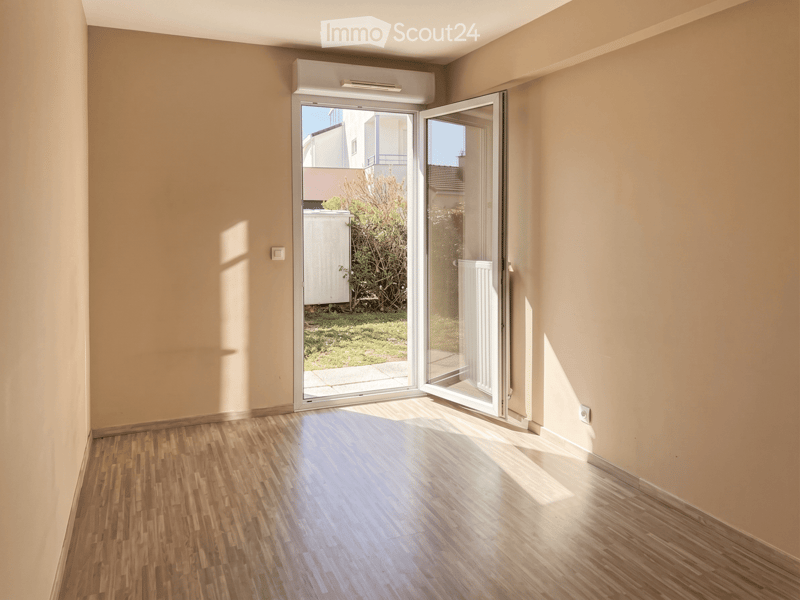 Empty room with wooden flooring, light-colored walls, and large sliding glass doors leading to an outdoor area.