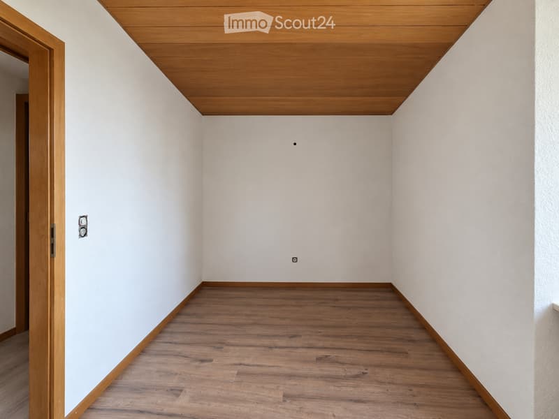 Empty room with light wooden flooring, white walls, and a wooden ceiling. No furniture or equipment is present.