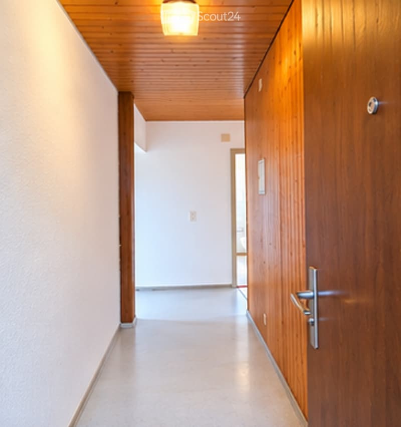 Bright, clean hallway with wooden ceiling and walls, white walls, and a single light fixture.