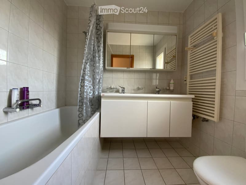 white bathtub, large mirror, white cabinet, tile flooring, white toilet