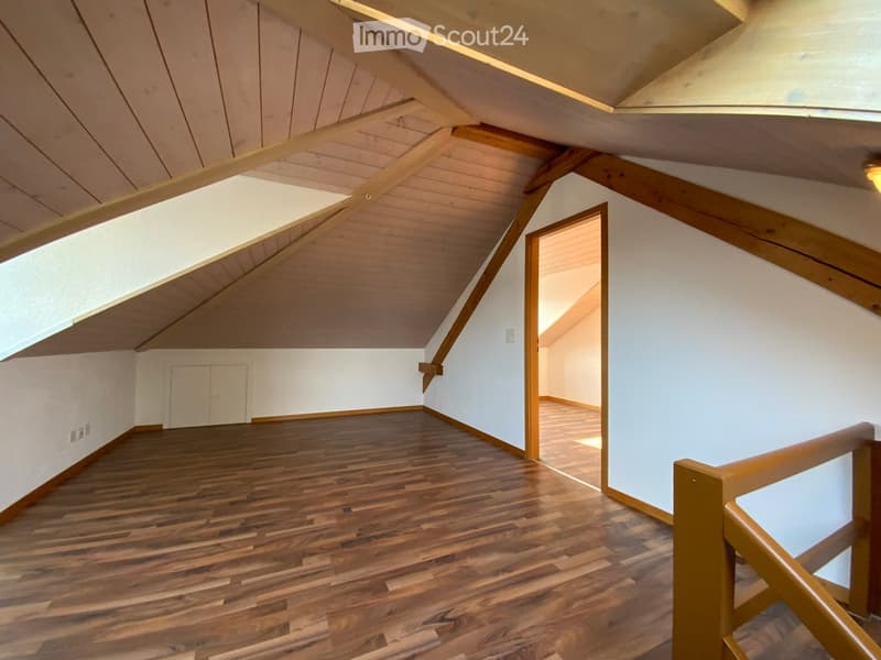 Unfurnished attic room with wooden floors, wooden ceiling beams, and white walls